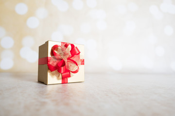 Christmas design with present in gold wrapping and red ribbon with space for text