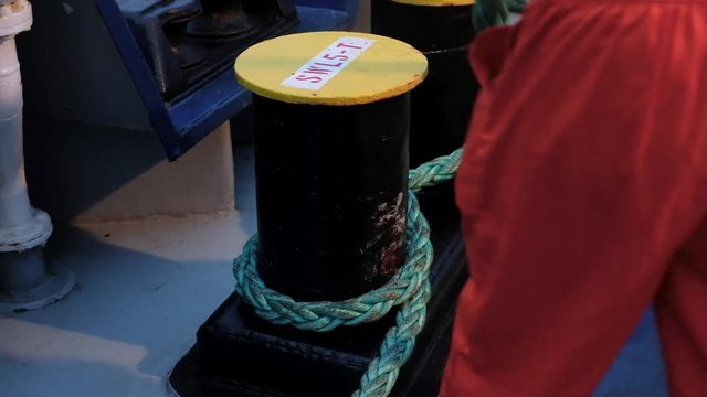 Sailor is wrapping the rope during mooring of the ship