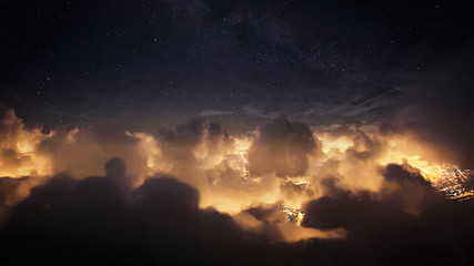 Flying over the deep night clouds with dark sky. Flight through moving cloudscape over night city lights. Perfect for posters, background, digital composition.