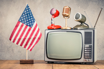 USA flag, retro old microphone and TV set front concrete wall background. Vintage instagram style filtered photo