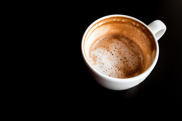 Half a cup of Hot milk coffee and soft froth in white ceramic cup