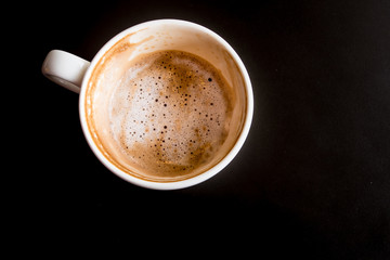 Half a cup of Hot milk coffee and soft froth in white ceramic cup