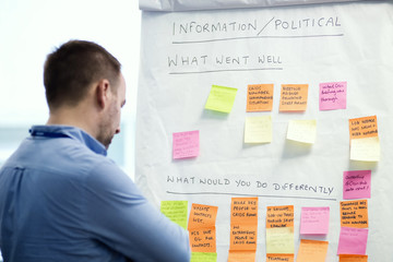 man  look at post it and information stick on flipchart, focus on flipchart