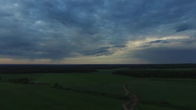 View from drone field with sunset sky nature landscape background. Footage. Aerial view of rural area with forest road in summer sunset