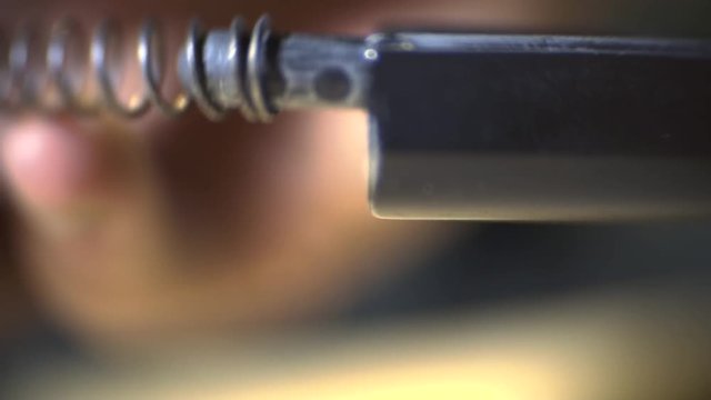 Macro shooting as a man's hands compile a gun and put on a fighting spring