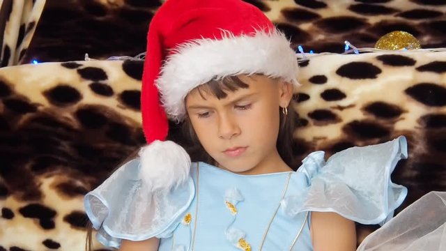 A sad child in a Santa Claus hat. Sad little girl on Christmas.