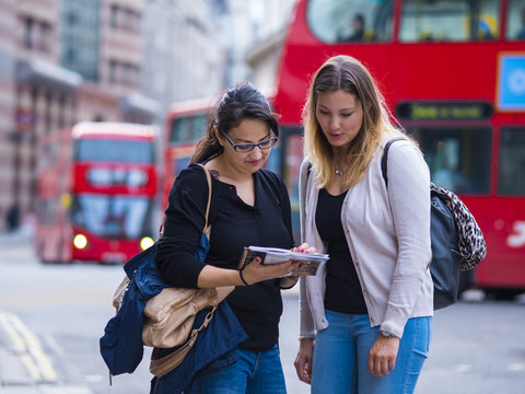 Two girls read a map in the city center of London
