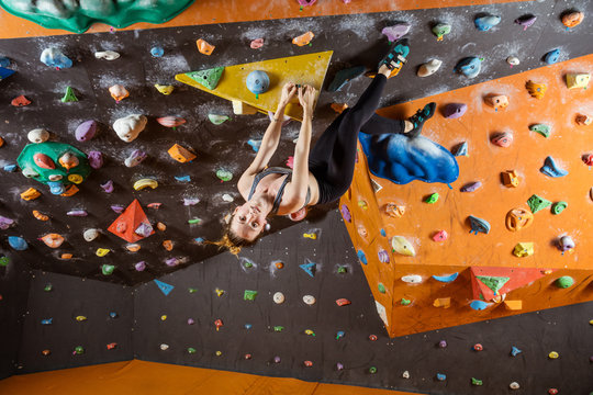 Young woman bouldering in climbing gym