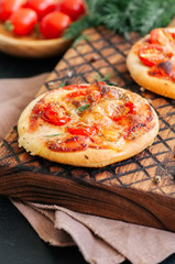 Mini pizzas margheritas on served on a wooden board. Wooden background