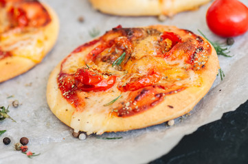 Mini pizzas margheritas on a parchment paper on a black stone background