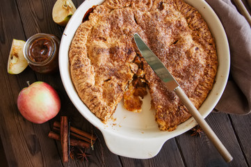 Traditional American apple pie in a ceramic form and ingredients on a wooden table. Close up and overhead view.