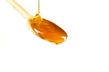 Spoonful of honey on the wooden spoon on the white background