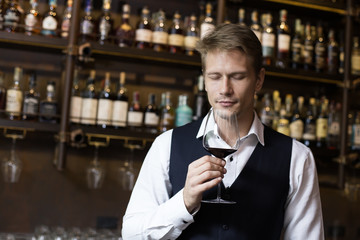 Handsome sommelier man smelling wine at restaurant, Man smelling Wine in wineglass, Man with Sommelier Concept.