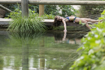 Girl lying on the footbridge of a lake.
