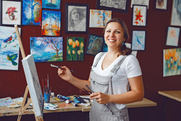 Portrait of young beautiful middle age white Caucasian woman artist drawing painting in art studio with acrylic paints on canvas. Lifestyle activity hobby concept