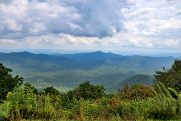 Blue Ridge Parkway scenic view. Summer landscape with cloudy sky over the road with car in motion passing through Great Smoky Mountains scenic highway Blue Ridge Parkway at North Carolina, USA.