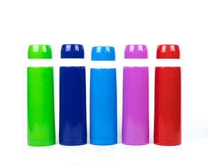 Green, blue, pink and red thermos bottles on white background with copy space