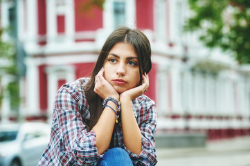 Pensive girl sitting in the city