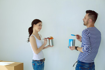 Portrait of happy smiling young couple painting interior wall of new house. young couple