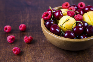 Ripe berries in a plate on a wooden table.