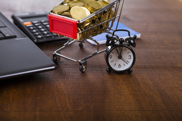 Shopping trolley with coins,  laptop and alarm clock
