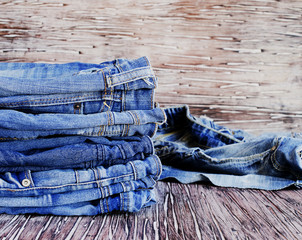 stack of jeans lying on a wooden table