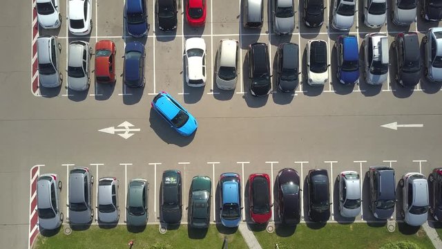 AERIAL TOP DOWN: Flying above female bad driver incapable to park a car on parking space in crowded parking lot. Woman having problems, unable to park a car in parking spot. Parking fail on parkspace