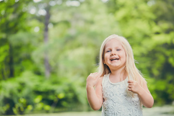 Portrait of laughing little girl in white dress