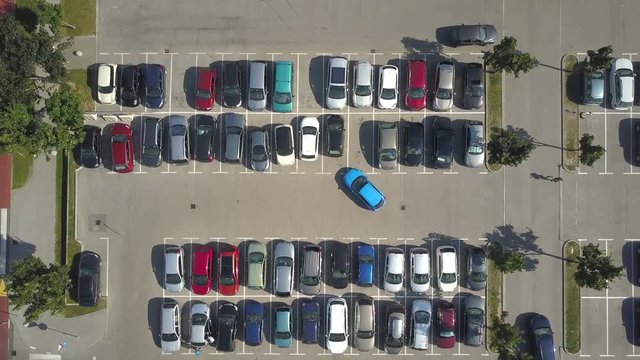 AERIAL TOP DOWN: Flying above female bad driver incapable to park a car on parking space in crowded parking lot. Woman having problems, unable to park a car in parking spot. Parking fail on parkspace