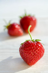 three strawberries on a wooden table