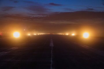 Empty runway at airport during a foggy evening