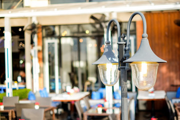 The vintage street lamp (lantern) shine near the outdoor restaurant for background or texture.