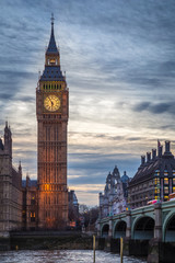 Fototapeta na wymiar London, England - The famous Big Ben and Houses of Parliament with iconic red double decker buses on Westminster Bridge at dusk
