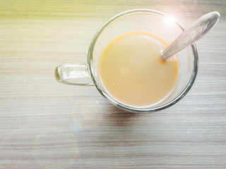 original asia coffee with cream in transparent cup with silver spoon on morning time with wooden texture table background