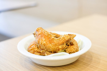 Delicious crispy fried chicken wings with green cabbage for snack serve on white plate for food background or texture - homemade concept.