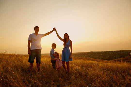 Happy family in the field at sunset.