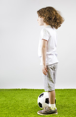 Boy with soccer ball on a gray background. Side view