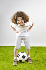 Little boy in white shorts and white shirt playing with a soccer ball. Fun boy laughs out loud.