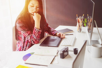 Young asian female designer using graphics tablet while working with computer at studio or office.