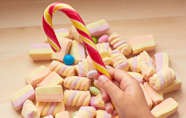  colored marshmallow on the table. A child holds a bright lollipop