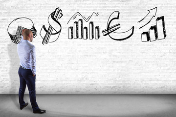 Businessman in front of a wall thinking about a hand drawn business interface - business concept