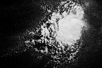 Pile of wheat flour isolated on black background, powder texture, top view with clipping path