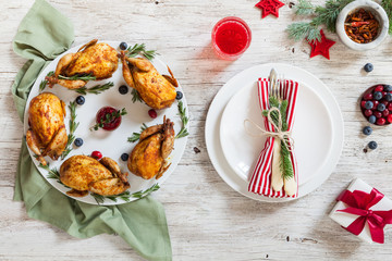 Christmas dinner table served with meat dish on plate with fork, knife and glass with compote on white wooden background. Top view. Spice, pepper, berries and furry spruce on a table.