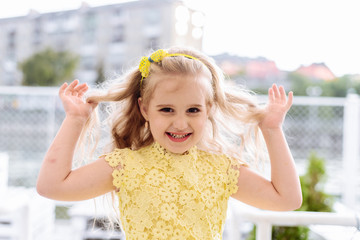 Portrait of a beautiful smiling little girl in a yellow dress with long blond hair