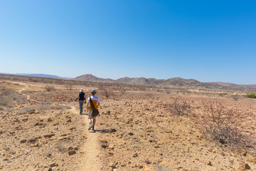 Khorixas, Namibia - August 26, 2016: Tourist and guide walking in the famous Petrified Forest National Park at Khorixas, Namibia, Africa. 280 million years old woodland, climate change concept
