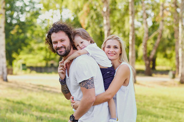 Fototapeta premium Happy family in the park. Father mother and son together in nature look at the camera.