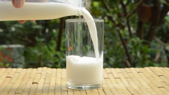 milk pouring from bottle to glass and hand lift up for drink