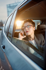 Naklejka premium business woman is driving in a car and use smartphone.