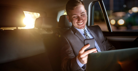 Businessman work on late night in back seat of car.