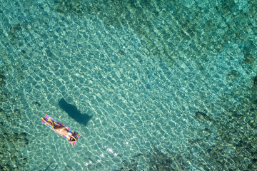 Obraz premium aerial view of a beautiful young woman in bikini on a matress in the sea